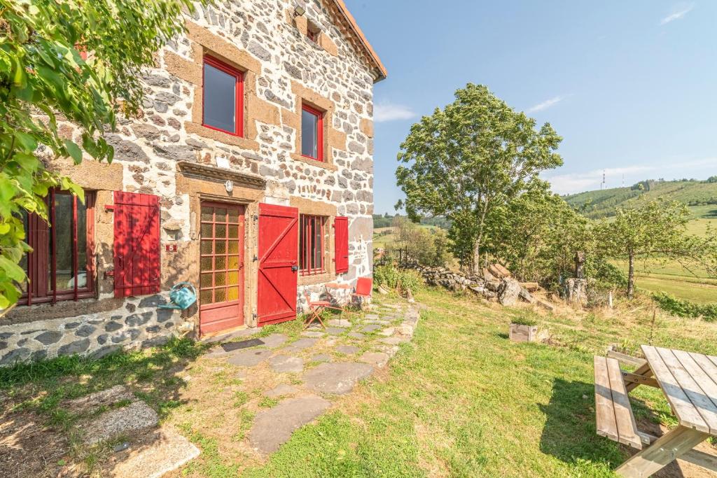 una vecchia casa in pietra con porte rosse e panca di La Maison de Freda - Maison avec vue montagne a Beauregard