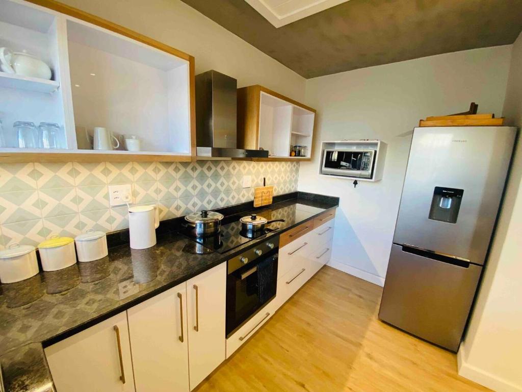 a kitchen with a stainless steel refrigerator and wooden floors at Central Apartment near Jetty Swakopmund in Swakopmund