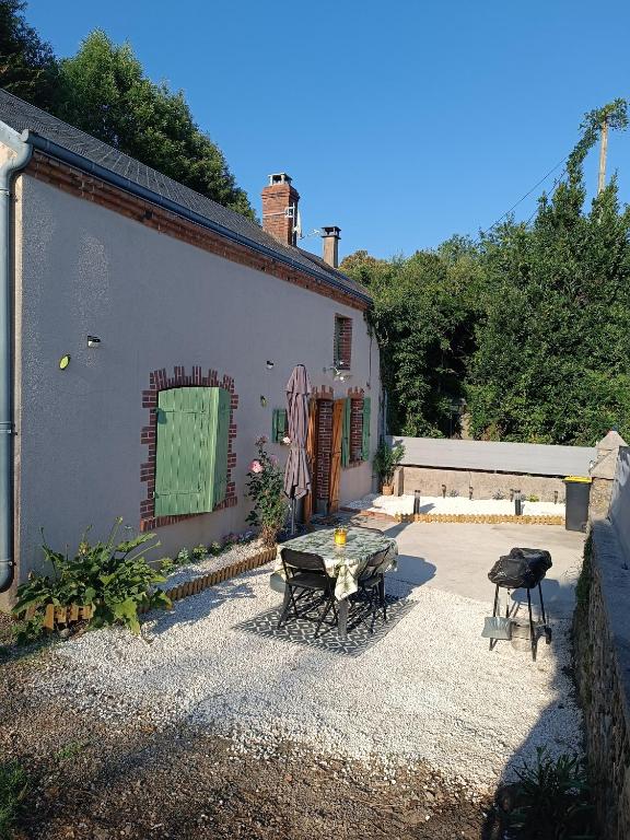 un patio avec une table et des chaises à côté d'un bâtiment dans l'établissement Maison berrichonne WiFi jardin linge, à Aigurande