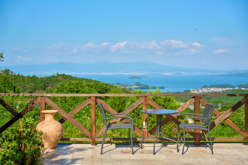eine Terrasse mit 2 Stühlen, einem Tisch und einer Vase in der Unterkunft 長崎の丘に浮かぶ天空テラス Villa 森の魔女 ,Villa Forest Witch in Nagasaki
