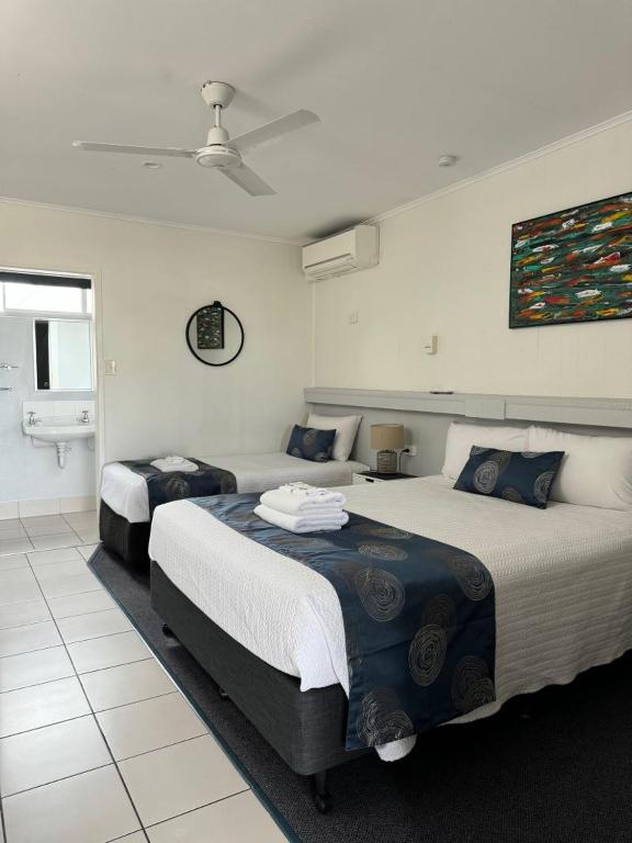 a bedroom with two beds and a bathroom at Charm City Motel in Bundaberg