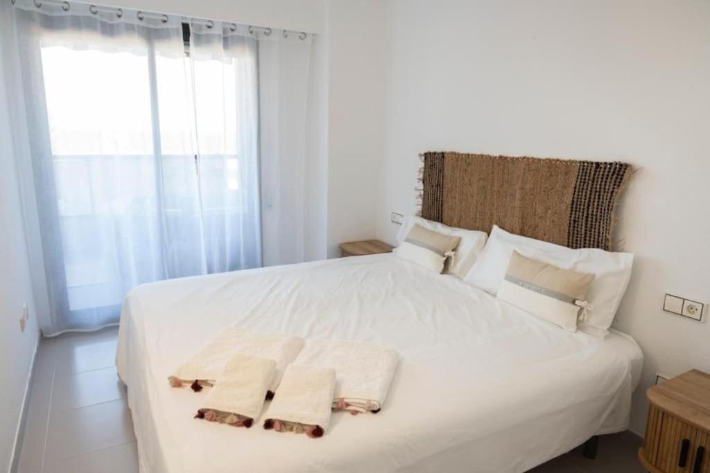 a bedroom with a white bed with towels on it at Espacio2,1a línea,jacuzzi,piscina in Cullera