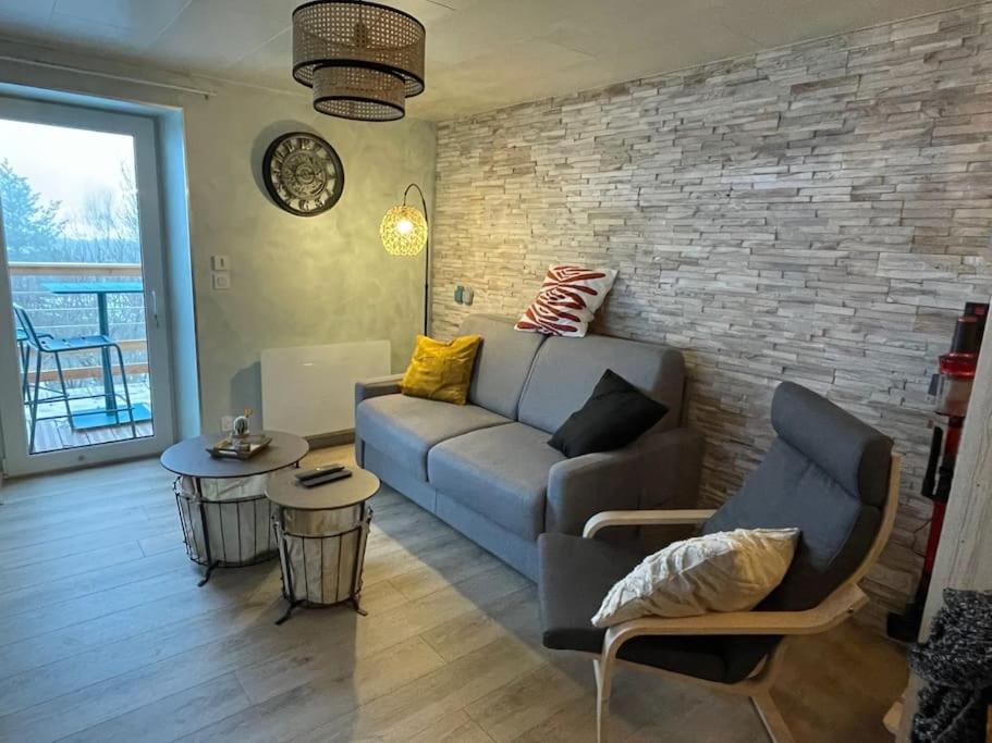 ein Wohnzimmer mit einer Couch und einer Ziegelwand in der Unterkunft Charme et quiétude au cœur du Haut-Jura in Lamoura
