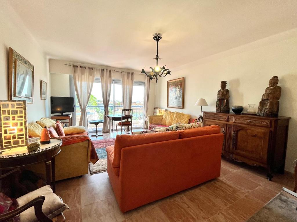 - un salon avec un canapé orange et une télévision dans l'établissement Méditerranée by Welcome to Cannes, à Cannes