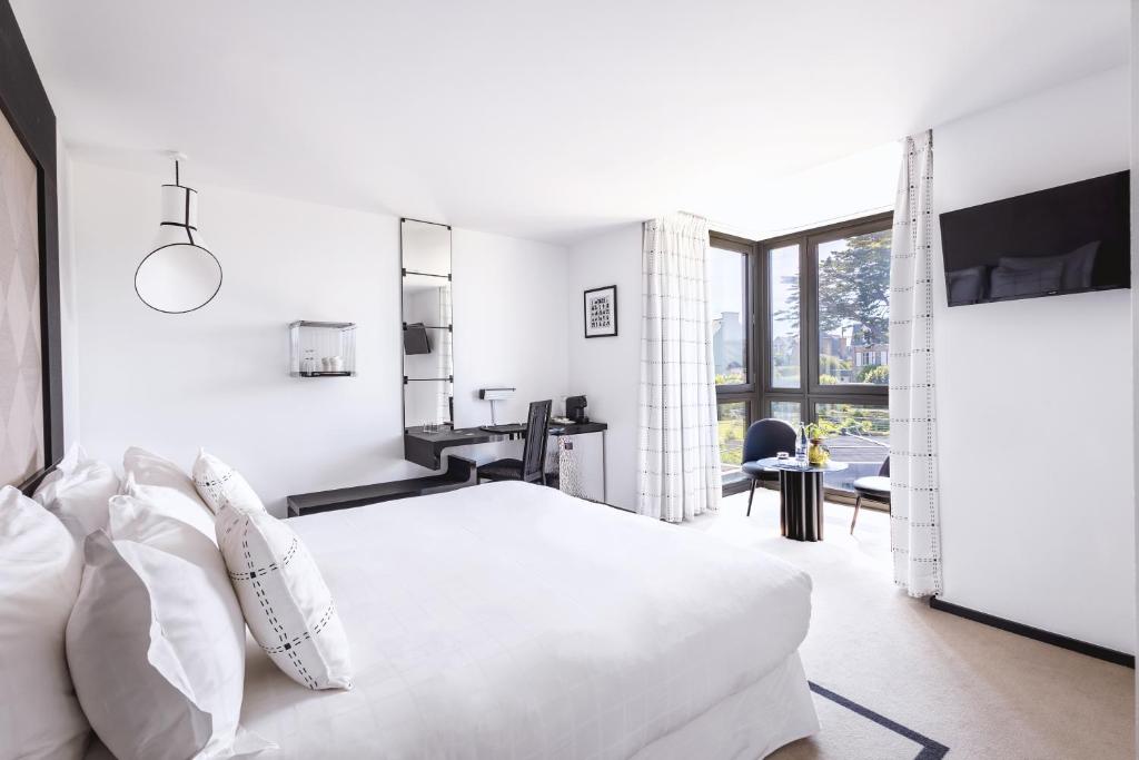 a white bedroom with a bed and a desk at L'Agapa Hôtel - Spa Codage in Perros-Guirec