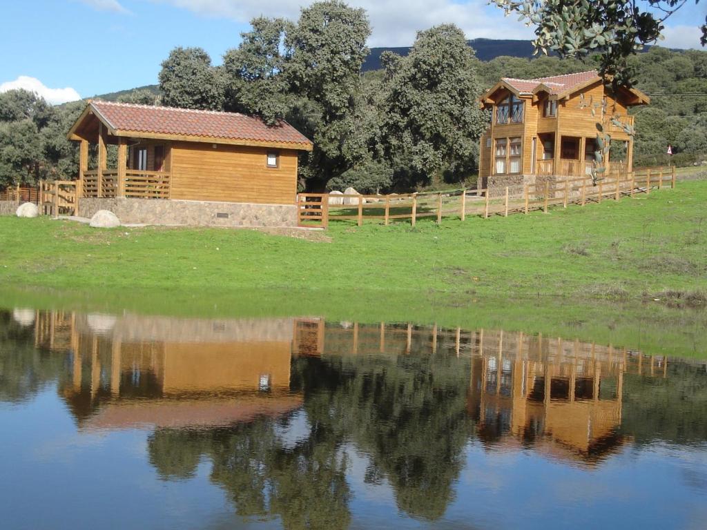 una casa de madera sentada junto a un cuerpo de agua en Complejo Rural Los Jarales, en Navamorcuende