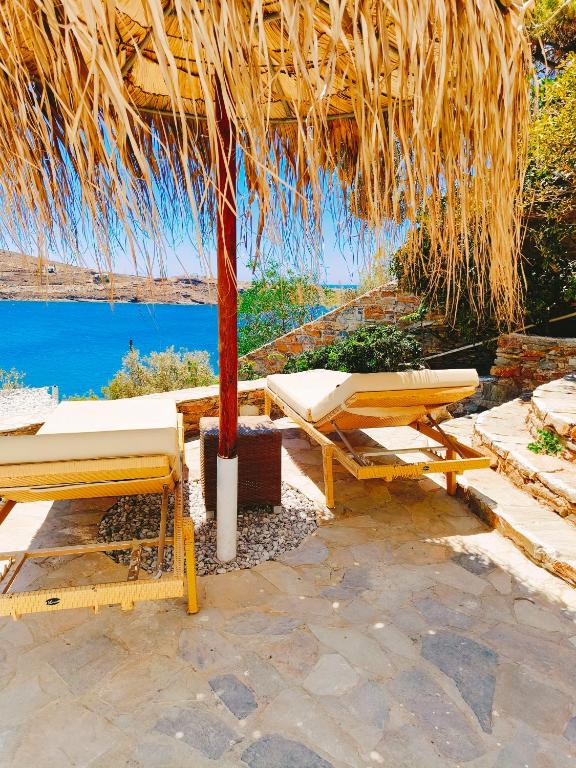 a straw hut with two lounge chairs and a table at Villa Elena Kythnos in Mérikhas