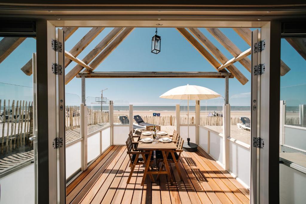 - une table à manger sur une terrasse avec vue sur la plage dans l'établissement Thalassa Beach Houses, à Zandvoort