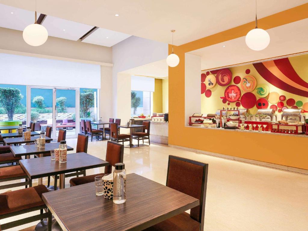 a dining room with tables and chairs and a restaurant at ibis Pune Viman Nagar - An Accor Brand in Pune
