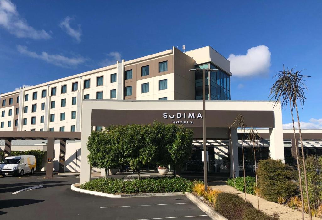 a large white building with a parking lot in front of it at Sudima Auckland Airport in Auckland