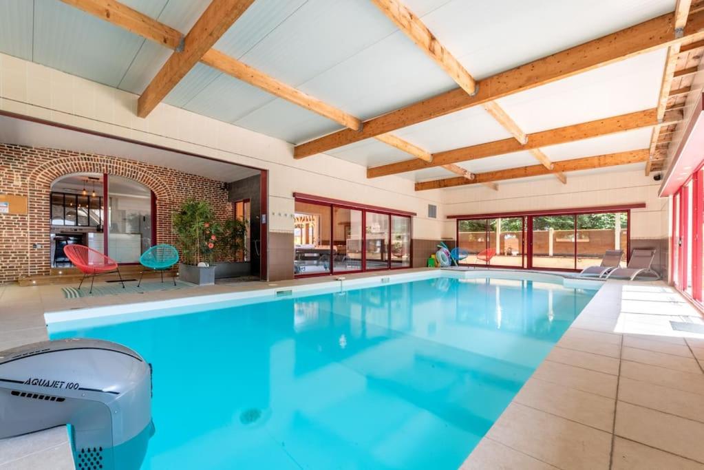 - une grande piscine d'eau bleue dans une maison dans l'établissement Piscine intérieure, SPA et Jeux open for 15 guests, à Gerponville