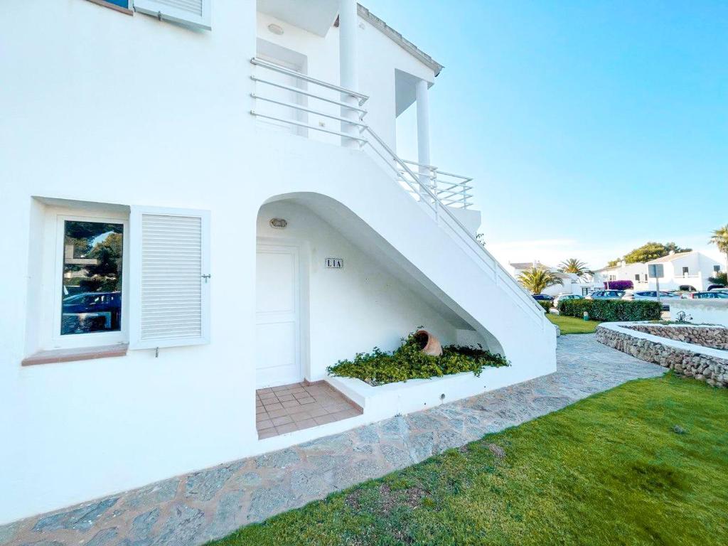Biały dom z białymi drzwiami i dziedzińcem w obiekcie Apartamento Lia en Port Addaia, piscina y barbacoa, perfecto para vacaciones w mieście Port d'Addaia