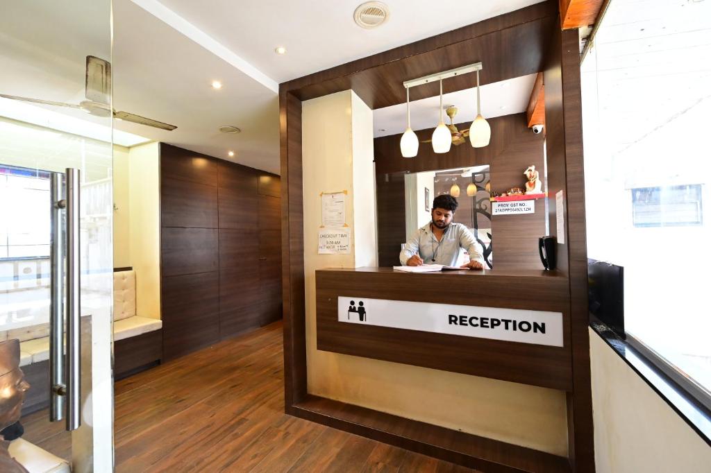 a man standing behind a reception counter in a restaurant at Aasra Lodge in Ratnagiri