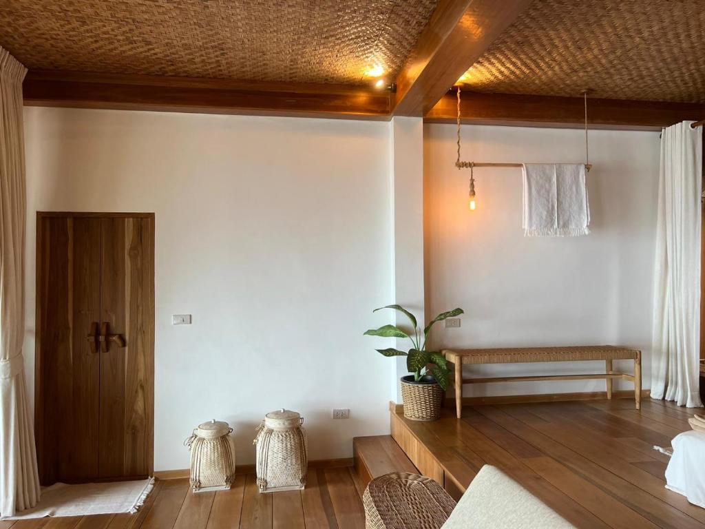 a living room with a bench and wooden floors at Why Nam Beach in Haad Yuan
