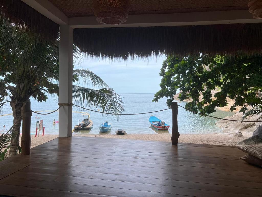 a porch with a view of the beach and boats at Why Nam Beach in Haad Yuan