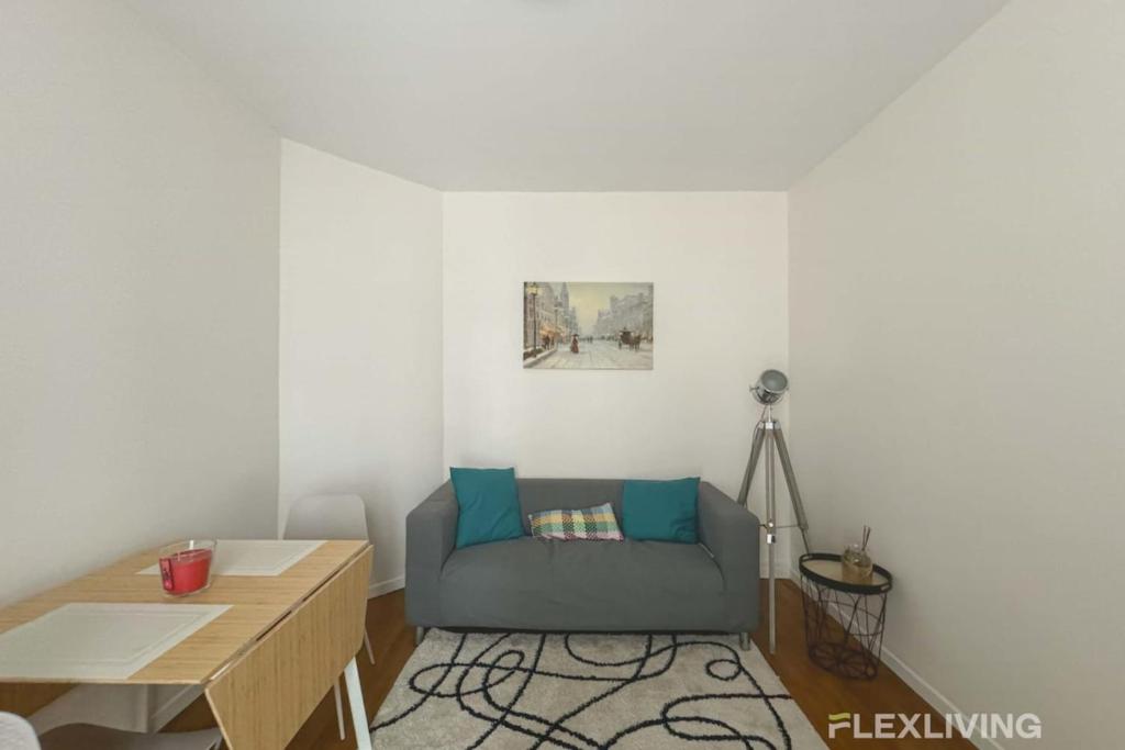 un salon avec un canapé bleu et une table dans l'établissement Flexliving - room - Villette, à Paris