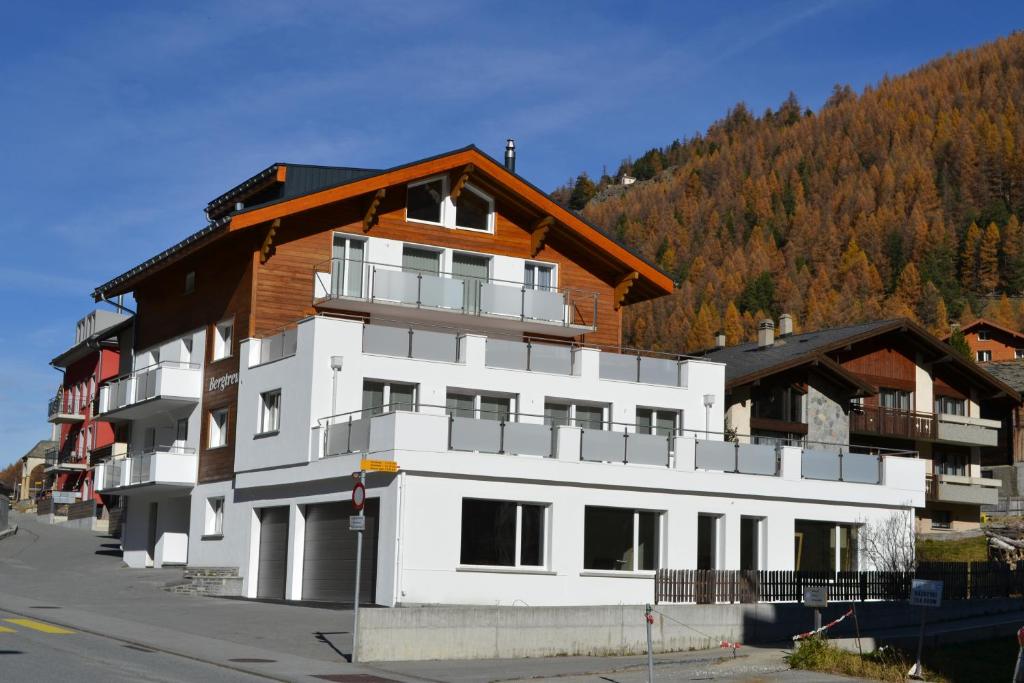 een groot wit gebouw met een houten dak bij Haus Bergtreu in Saas-Grund