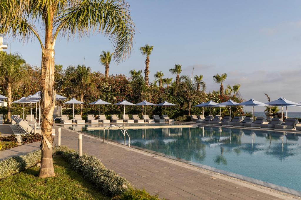 a swimming pool with chairs and umbrellas at a resort at Ivi Mare - Designed for Adults by Louis Hotels in Paphos