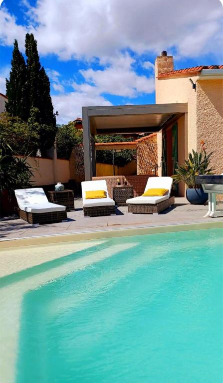 - une piscine avec 2 chaises longues à côté d'une maison dans l'établissement La SIRENADE, à Canet
