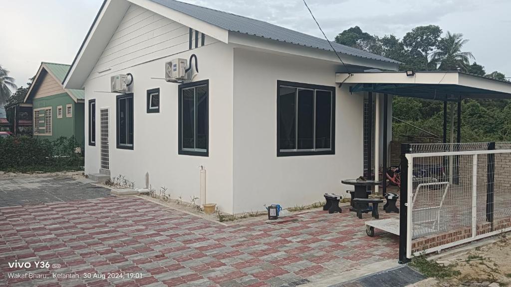 a small white house with a patio and a grill at Andalus Cottage in Wakaf Baharu