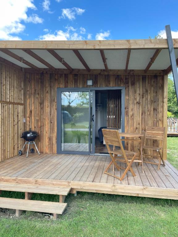 un patio avec une table et des chaises sur une terrasse dans l'établissement Chalet Camping du grand fay, à Saint-Père-en-Retz