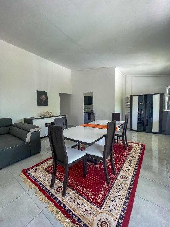a dining room with a table and chairs on a rug at Villa trinité in La Trinité