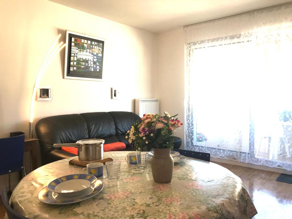 ein Wohnzimmer mit einem Tisch und einem Ledersofa in der Unterkunft LE CASINO DES FLEURS - Hypercentre - Parking - Balcon in Vichy