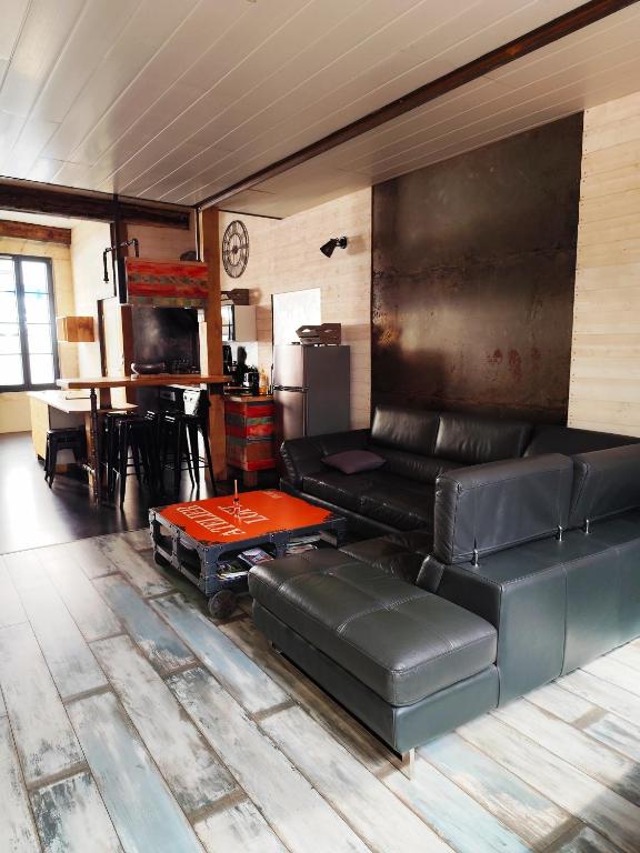 a living room with a leather couch and a table at la rénovée d'antan bis in Avallon