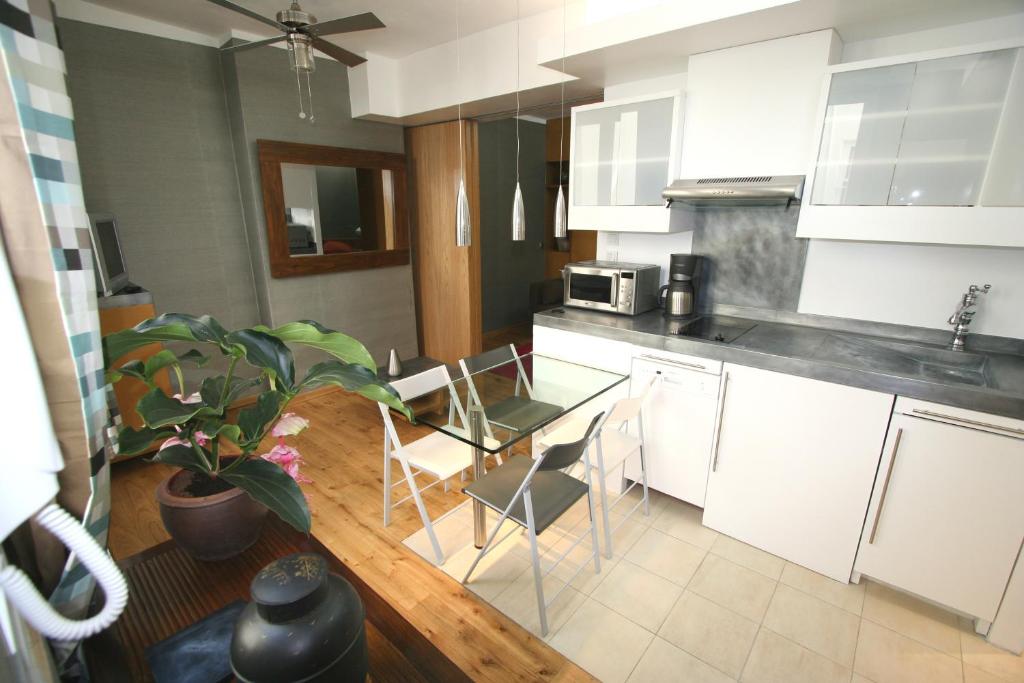 a kitchen with white cabinets and a table and chairs at Paris Interiors Rentals - Le Marais LOUVRE - NOTRE DAME in Paris