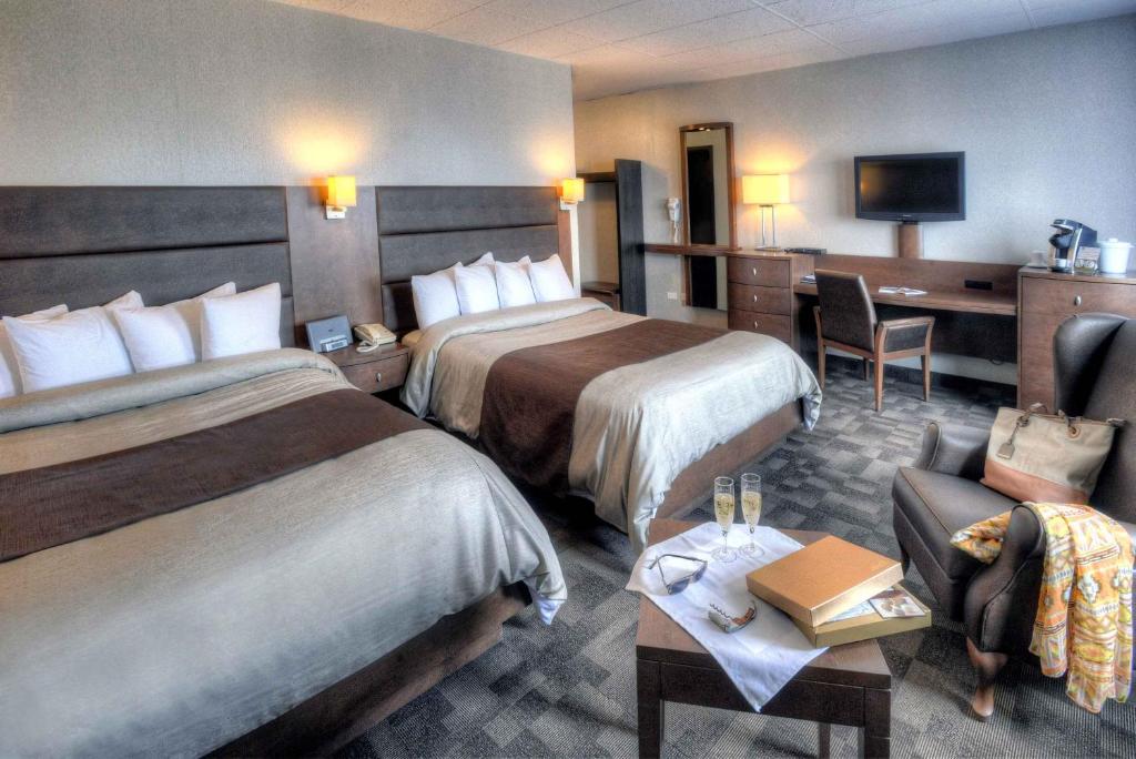 a hotel room with two beds and a desk at Hotel Continental Centre-Ville in Val-dʼOr