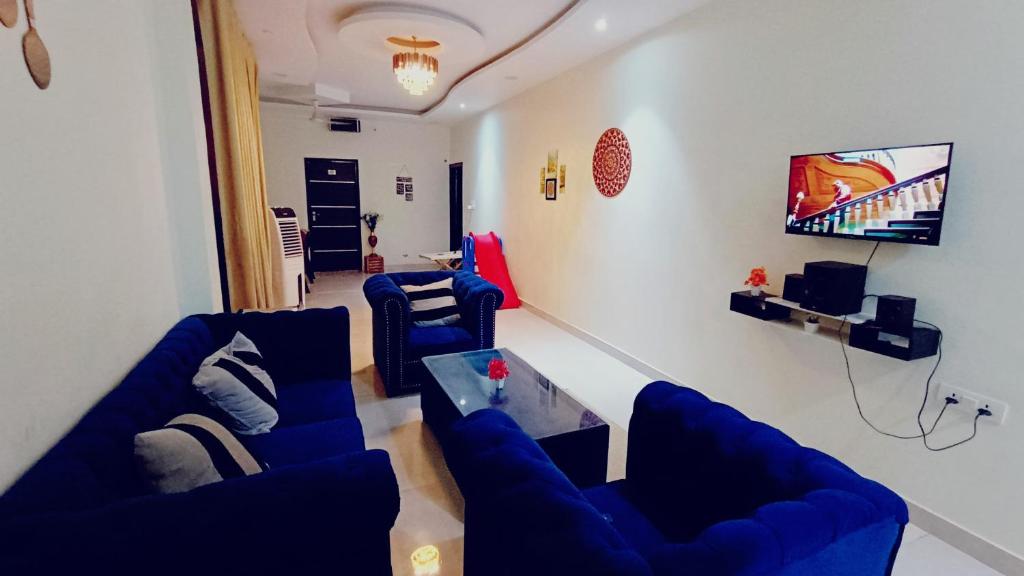 a living room with blue couches and a tv at TWO BHK ABODE in GOLF CITY LUCKNOW in Lucknow