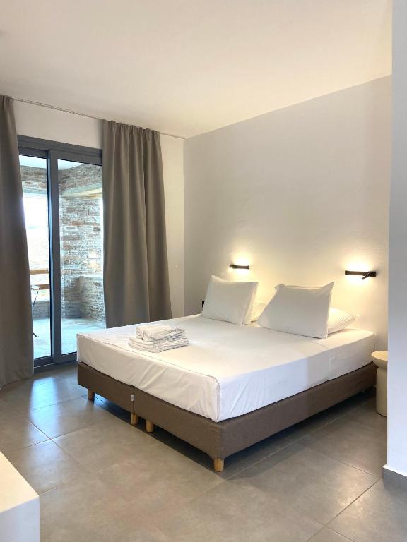 a bedroom with a bed with white sheets and pillows at Spanos Apartments in Agios Petros