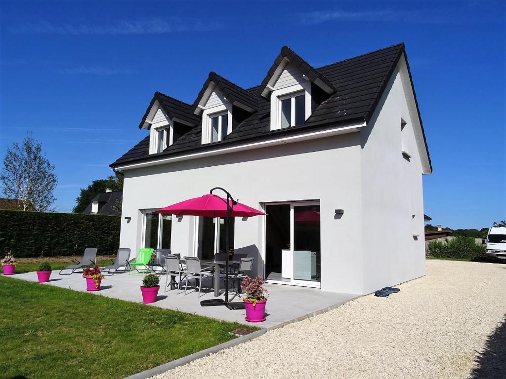 une maison blanche avec un parasol et des chaises rouges dans l'établissement Villa Rubis Varengeville, à Varengeville-sur-Mer