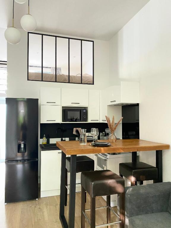 une cuisine avec une table en bois et des chaises noires dans l'établissement Appartement indép cosy avec jardin, à Saint-Denis
