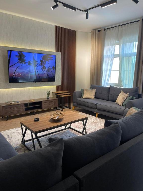 a living room with two couches and a tv at Eleganza Marina Apartments KAEC in King Abdullah Economic City