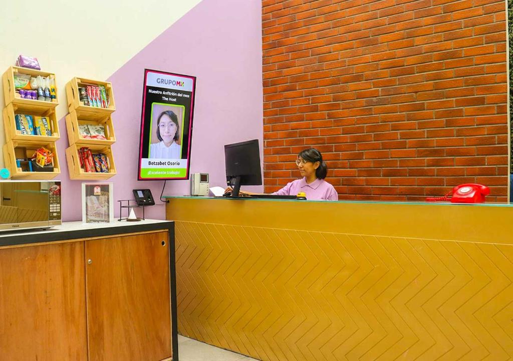The reception desk sits against a brick wall beside shelves of books and small goods.