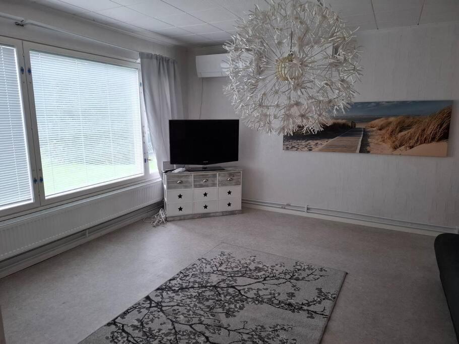 a living room with a television and a chandelier at Oulaisten mökkeröinen in Oulainen