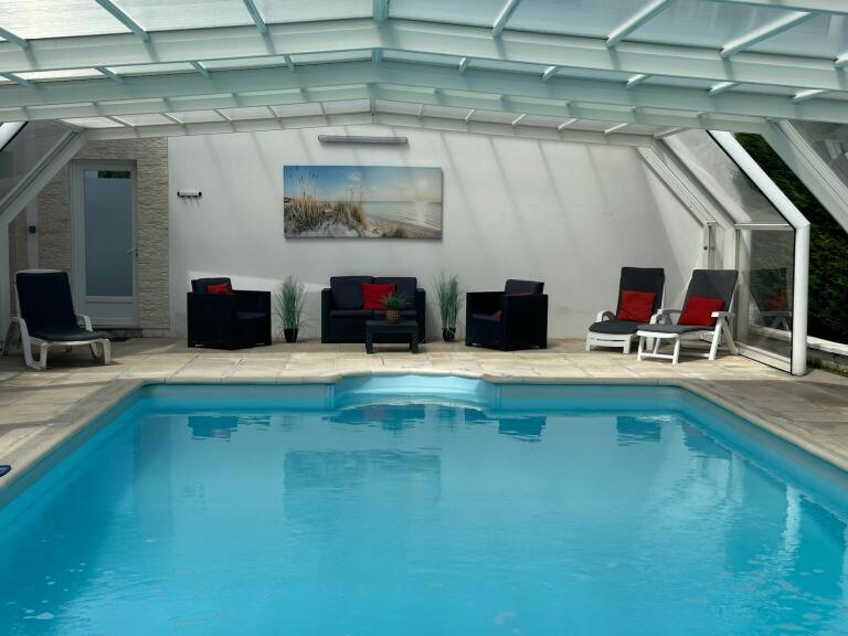 une grande piscine avec des chaises et un canapé dans l'établissement Gîte avec Piscine et spa, à Éperlecques