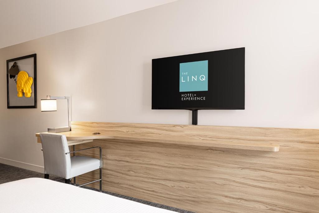 a room with a desk with a television on a wall at The LINQ Hotel and Casino in Las Vegas