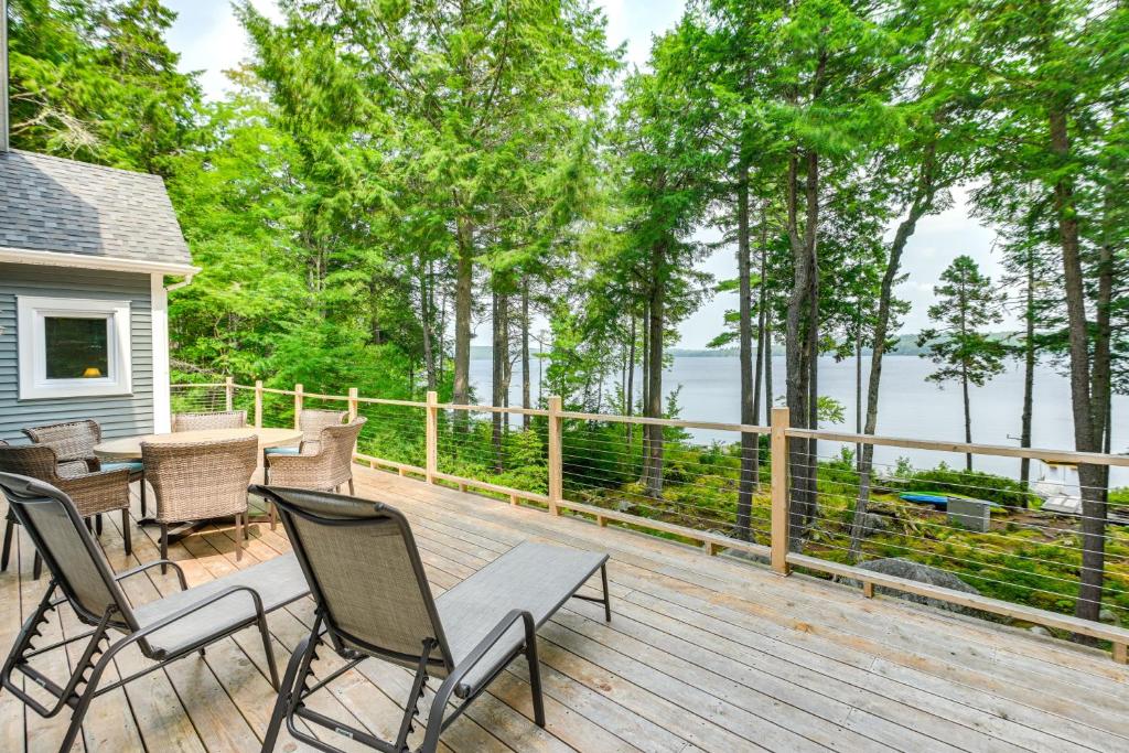 a deck with chairs and a table with a view of the water at Coastal Branch Lake House with Dock and Game Room in Orland
