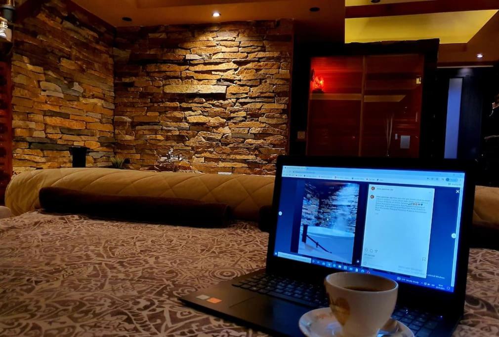 SremčicaにあるStone Spa Apartmanのソファに座ってコーヒーを飲みながらノートパソコンを見る