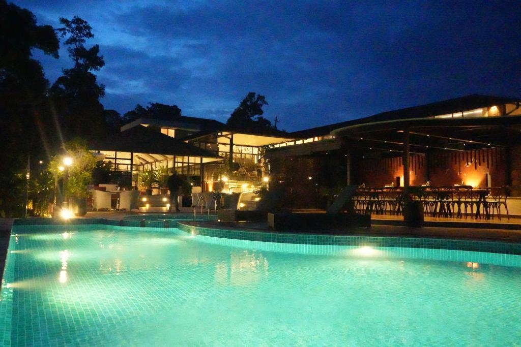 a large swimming pool at night with a building at Inika in Ponnampet
