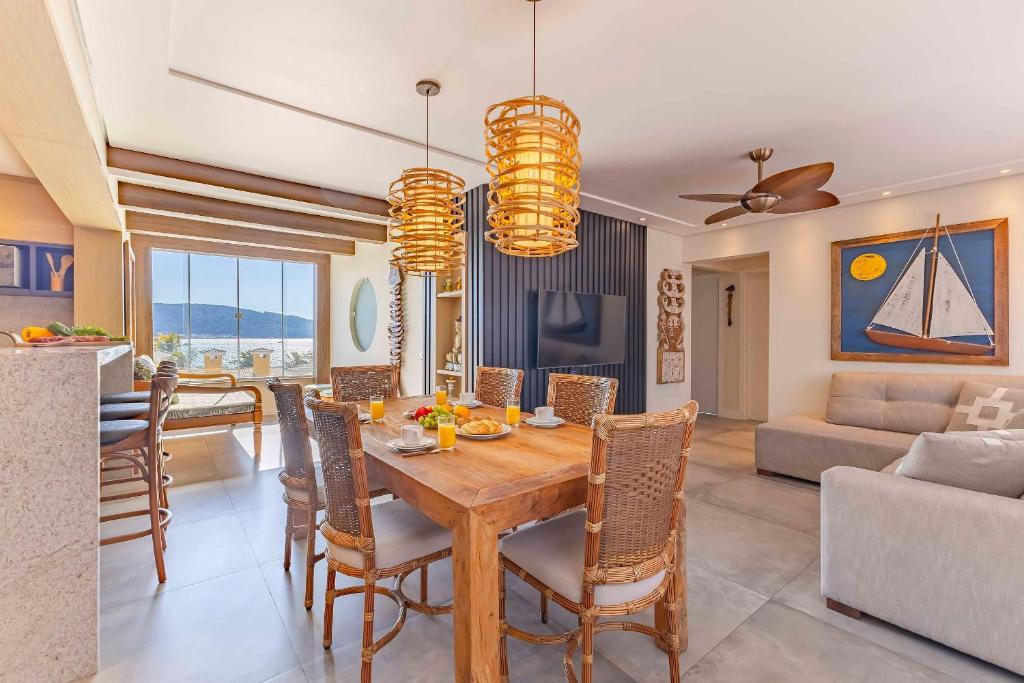 a dining room and living room with a table and chairs at Exclusivo Apartamento com Vista Mar e Saída Direta para Praia in Bombinhas