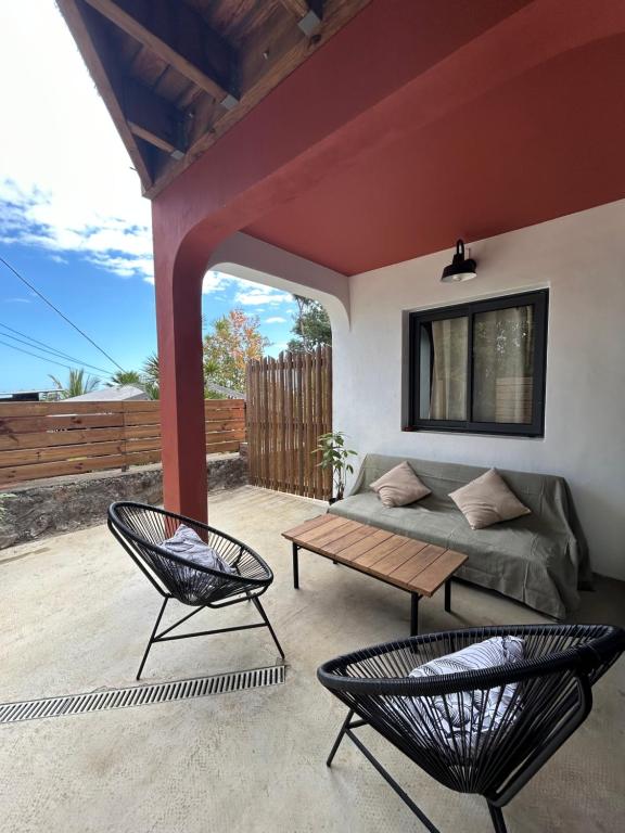 un patio con sofá, 2 sillas y una mesa en Mon Ti Piton, en Saint-Leu