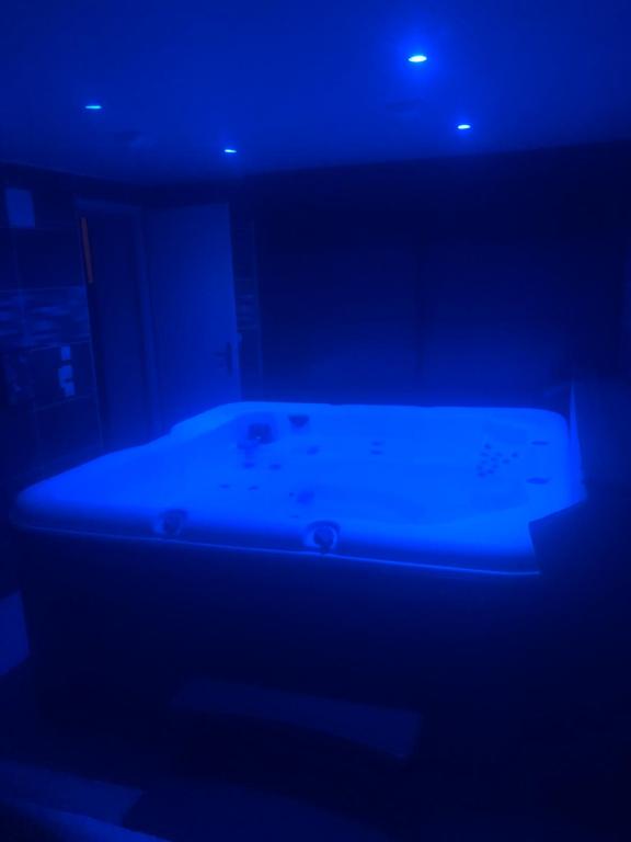 - un lit dans une chambre sombre avec une lumière bleue dans l'établissement L appartement soleil de willerval, à Willerval