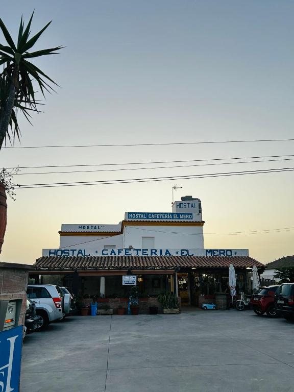 a building with cars parked in a parking lot at Hostal Cafeteria El Mero in Zahora