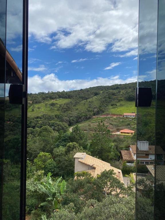 une vue d'une colline depuis une fenêtre en verre dans l'établissement Casa do Rafael, à Conceição da Ibitipoca