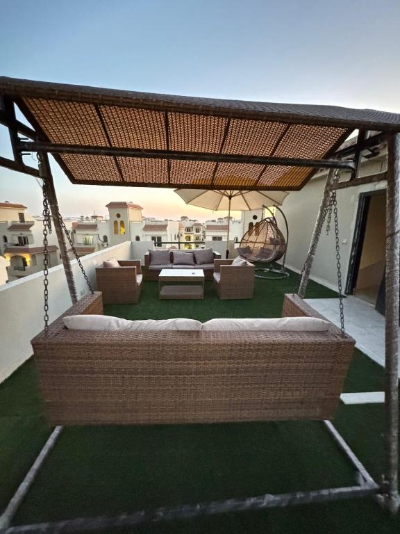 a patio with a swinging couch and chairs on a roof at Lasirena north coast Chalet With Roof , 3 rooms in Zāwiyat ‘Abd al Mun‘im
