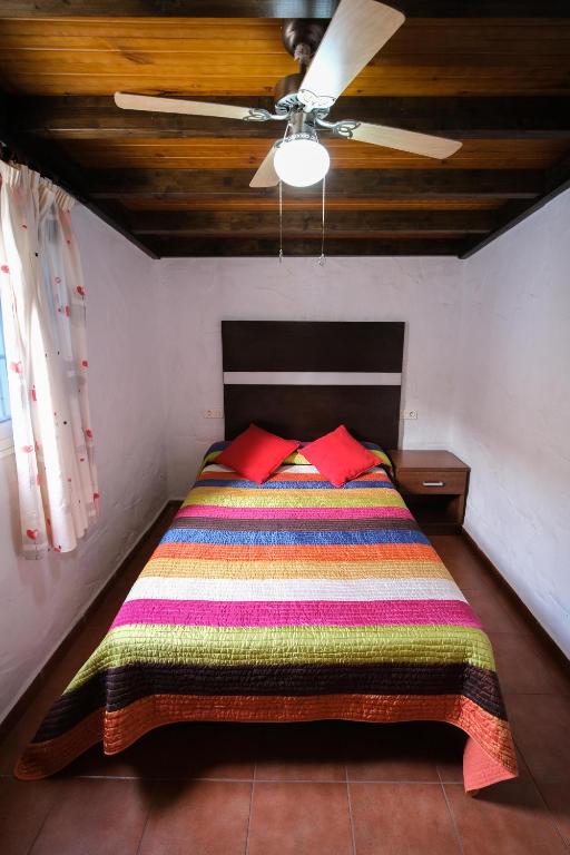 a bed with a colorful blanket and a ceiling fan at Club JM Lanzarote in Tabayesco