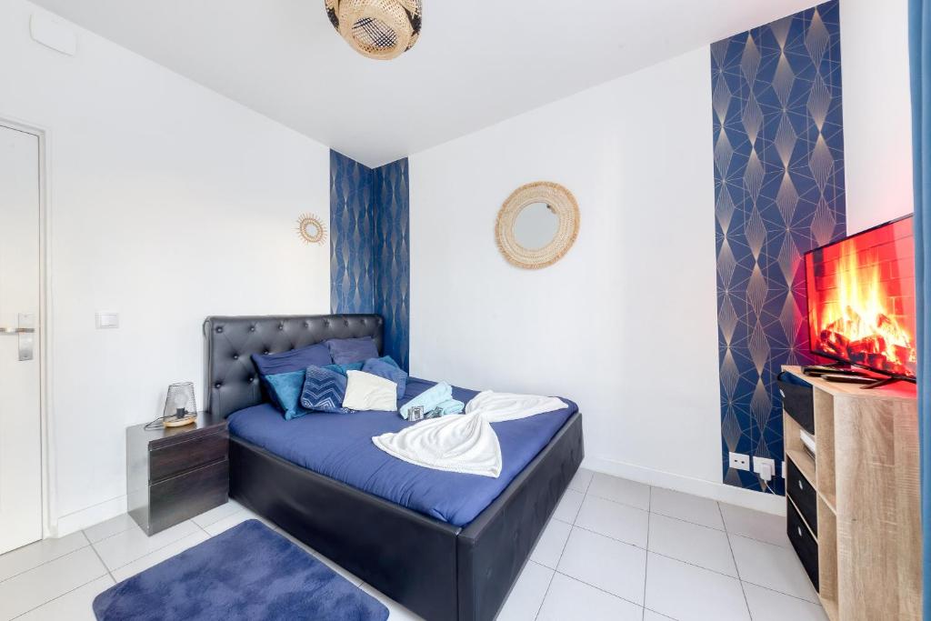 a bedroom with a blue bed and a tv at Appartement Moderne, proche Porte de Versailles et Gare de Clamart in Malakoff